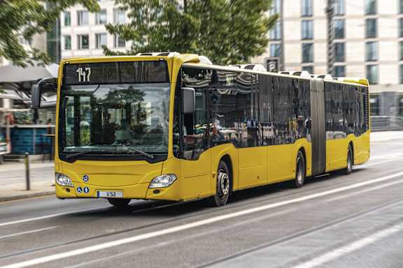 A yellow bus with the number 117 on the front is driving on a city street.