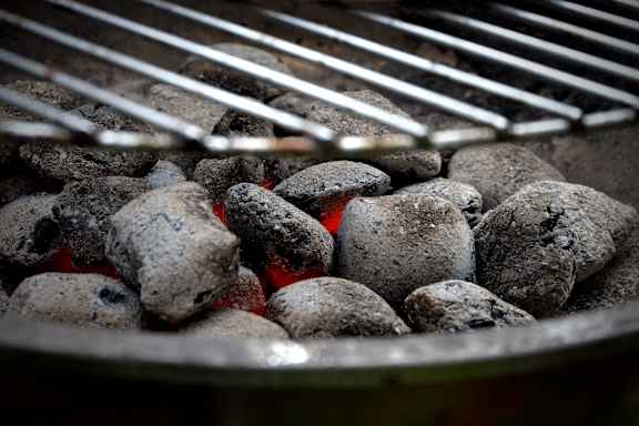 A close up of a grill with charcoal briquettes.