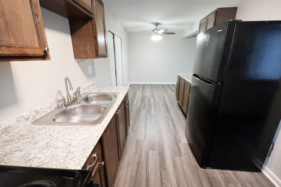 an empty kitchen with a black refrigerator and a sink at Crown Court Apartments, Florence, KY