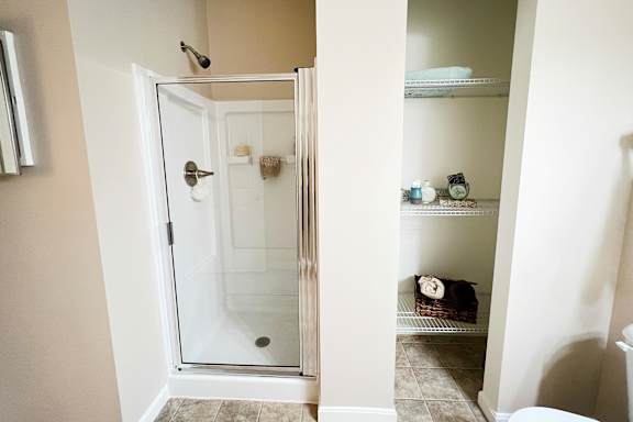A bathroom with a walk-in shower and a towel rack with towels.