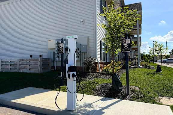 A parking sign is next to a charging station.