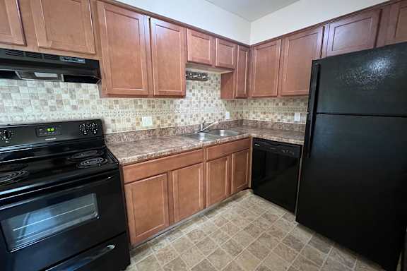 A kitchen with black appliances and brown cabinets.