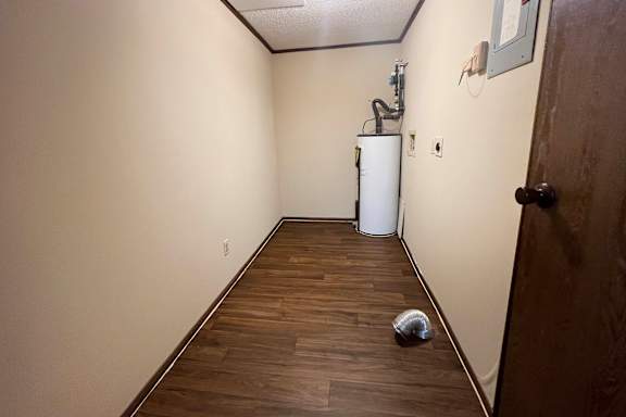 A long hallway with a white refrigerator and a trash can.