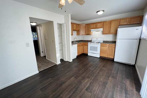 an empty kitchen with white appliances and wooden cabinets