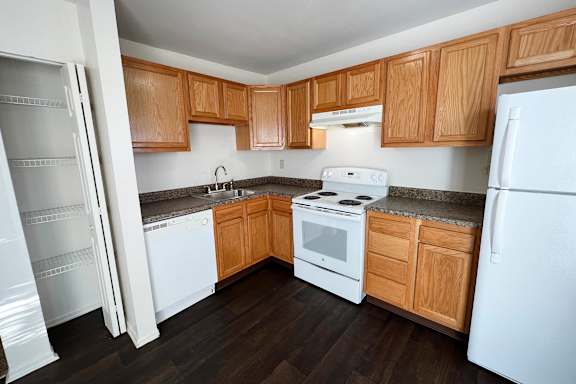 A kitchen with white appliances and wooden cabinets.
