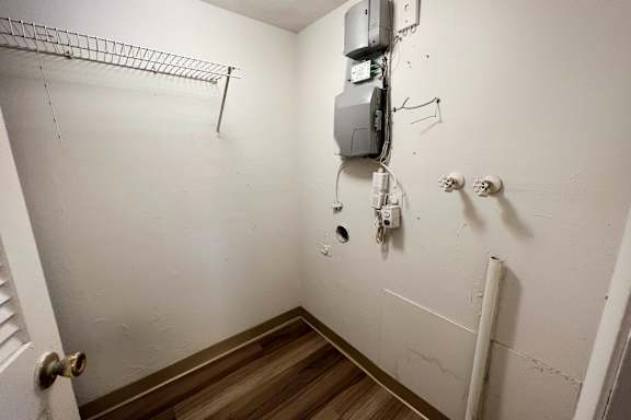 A white wall with a metal rack and a white pipe.