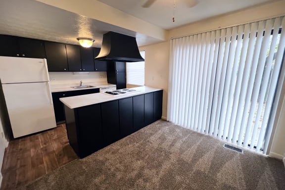 A kitchen with black cabinets and a white refrigerator at Miamisburg by the Mall, Miamisburg, 45342