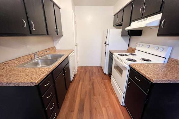 A kitchen with black cabinets and a white refrigerator.