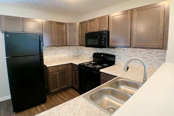 A kitchen with black appliances and wooden cabinets.