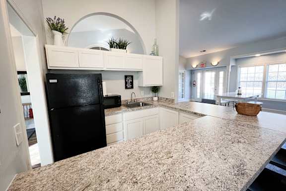 A kitchen with a black fridge and a granite countertop.