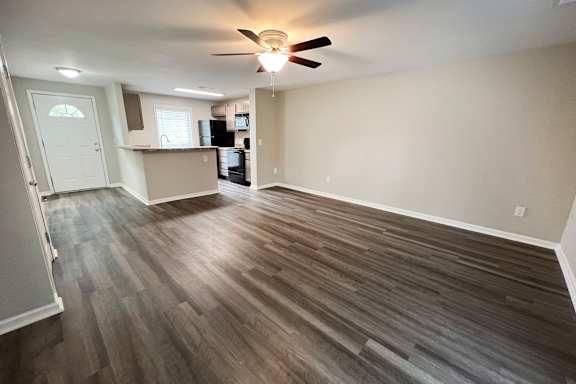 A room with a ceiling fan and wooden flooring.