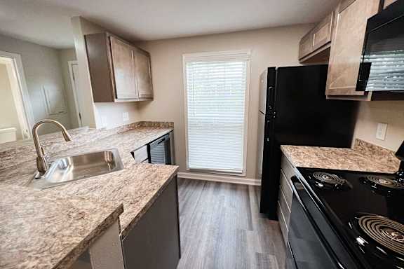 A kitchen with granite countertops and a black refrigerator.