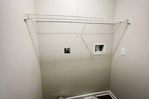 A white closet with a shelf and two electrical outlets.