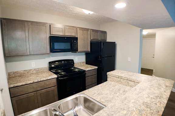 A kitchen with black appliances and granite countertops.