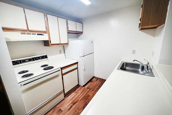A white kitchen with a stove, oven, and sink.