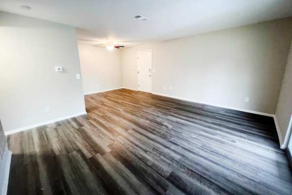 A room with wooden flooring and white walls.