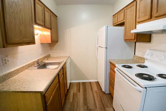 A kitchen with a white stove and wooden cabinets.