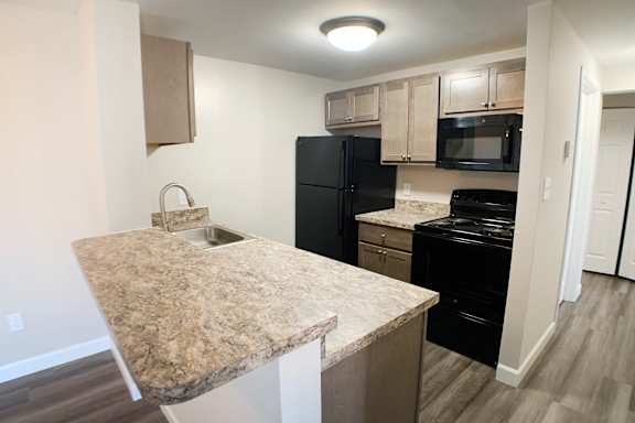 A kitchen with granite countertops and black appliances.