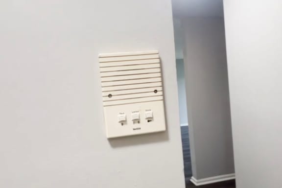 A white electrical panel with a switch and outlet is mounted on a white wall.