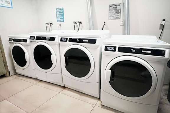 A row of white front load washing machines in a laundromat.