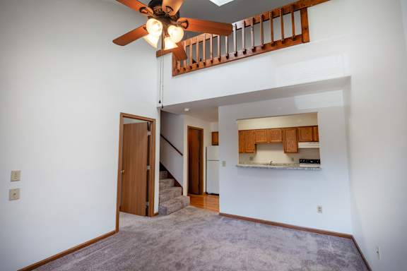 A room with a ceiling fan and a staircase leading to the upper floor.