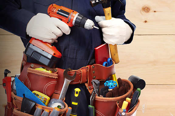 A man is holding a hammer and a drill.