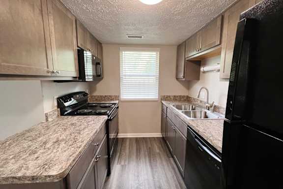 A kitchen with black appliances and wooden cabinets.