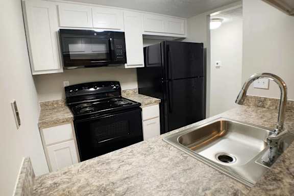 A kitchen with black appliances and a granite countertop.