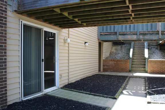 A patio area with a door and steps leading to a garage.