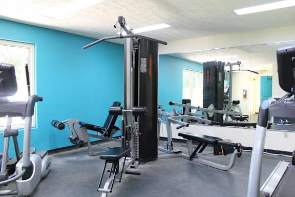 A gym with a variety of equipment including treadmills, weights, and exercise machines.