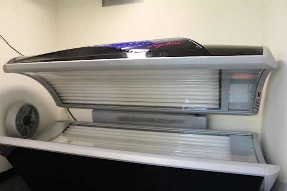 A large, modern, white freezer with a black top and a fan on the left side.