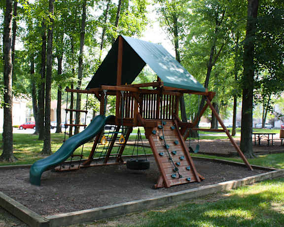 A playground with a green slide and a wooden structure.