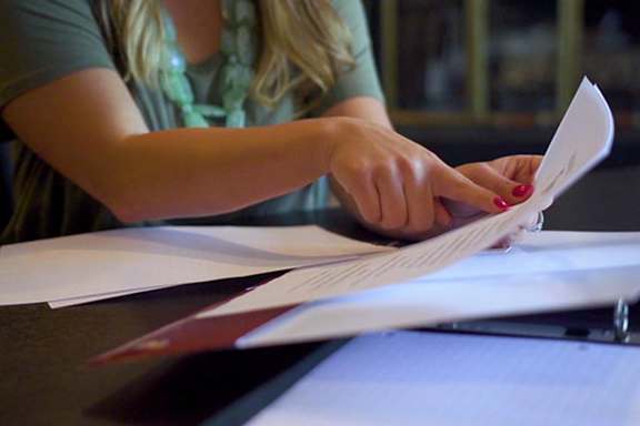 A person is reading a document while sitting at a table.