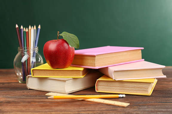 A stack of books with a red apple on top and a pencil on the side.
