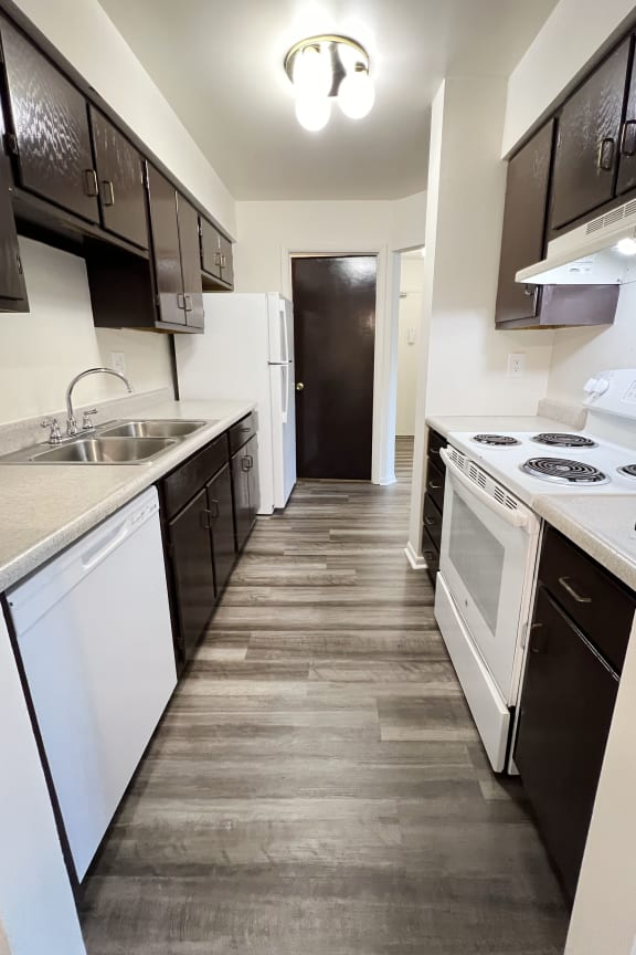 an empty kitchen with white appliances and black and white cabinets at Four Worlds Apartments, Ohio