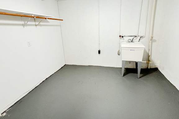 A white wall with a toilet and pipes.