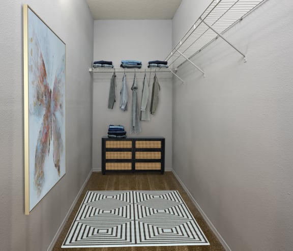 a walk in closet with clothes rack and a painting on the wall