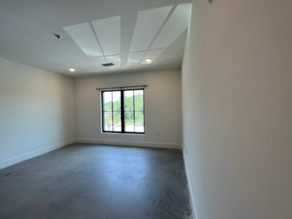 a empty room with a window and a concrete floor