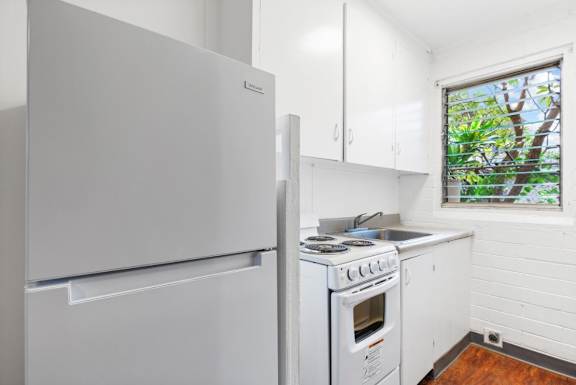 Floor Plan  A white fridge and stove in a small kitchen.