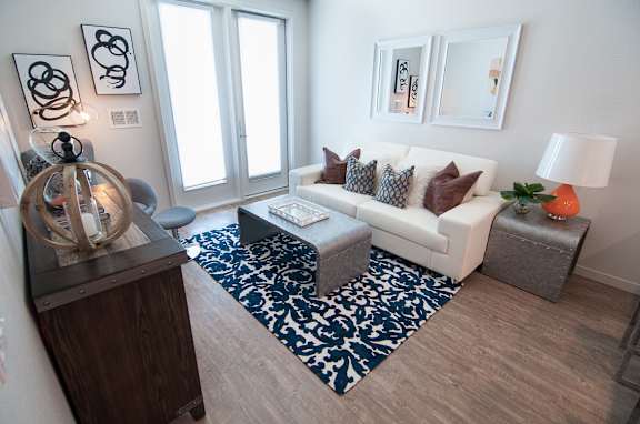 A living room with a white couch and a blue and white patterned rug.