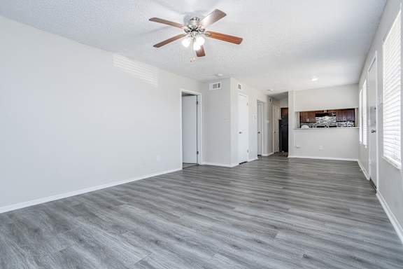A room with a ceiling fan and wooden flooring.