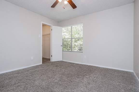 A room with a ceiling fan and a door leading to a balcony.