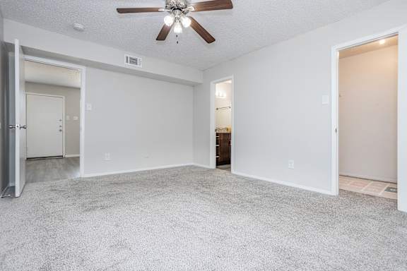 A spacious room with a ceiling fan and carpeted floor.