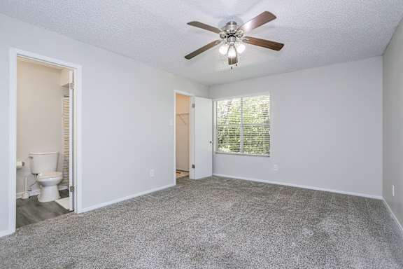 A room with a ceiling fan and carpeted floor.