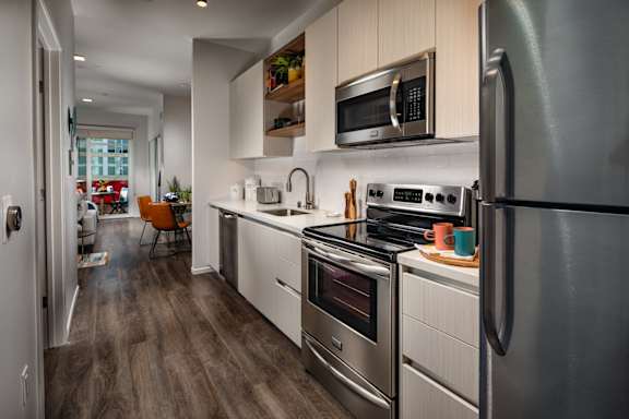 A modern kitchen with stainless steel appliances and wooden flooring.