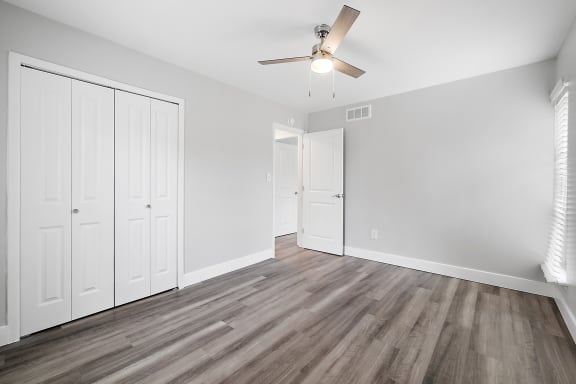 an empty living room with white walls and a ceiling fan