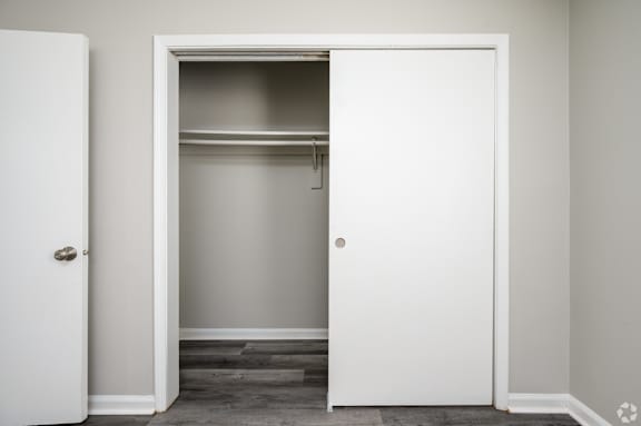 A white door is open to reveal a small closet with shelves.