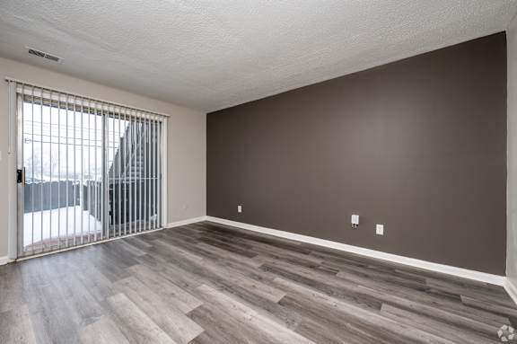 A room with a sliding glass door and wooden flooring.