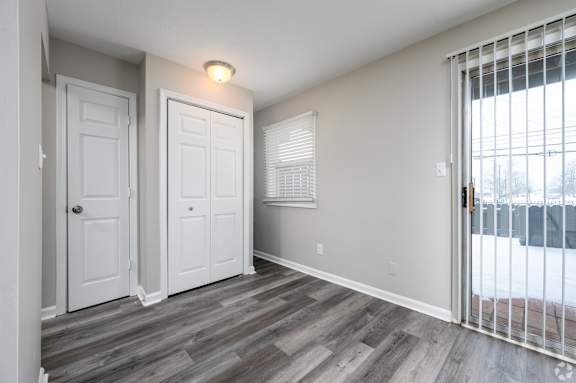 A room with two white doors and a window with blinds.