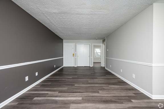 A long, empty hallway with a white door at the end.